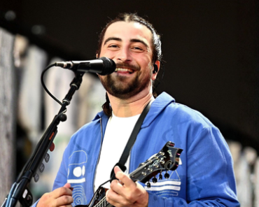 Noah Kahan performing live on stage with a guitar, kicking off his Great Divide Tour