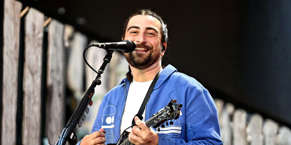 Noah Kahan performing live on stage with a guitar, kicking off his Great Divide Tour