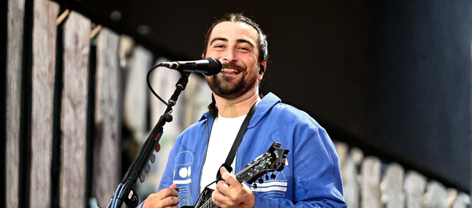 Noah Kahan performing live on stage with a guitar, kicking off his Great Divide Tour