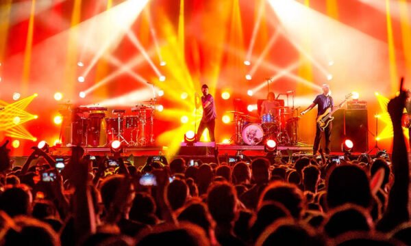 An opening act performing to a large concert crowd, representing artists whose careers outgrew their original headlining tour partner