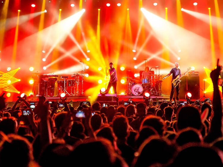 An opening act performing to a large concert crowd, representing artists whose careers outgrew their original headlining tour partner